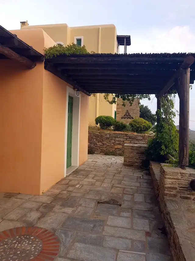 Αυλή κατοικίας βαμμένη σε απαλό πορτοκαλί, με πέργκολα